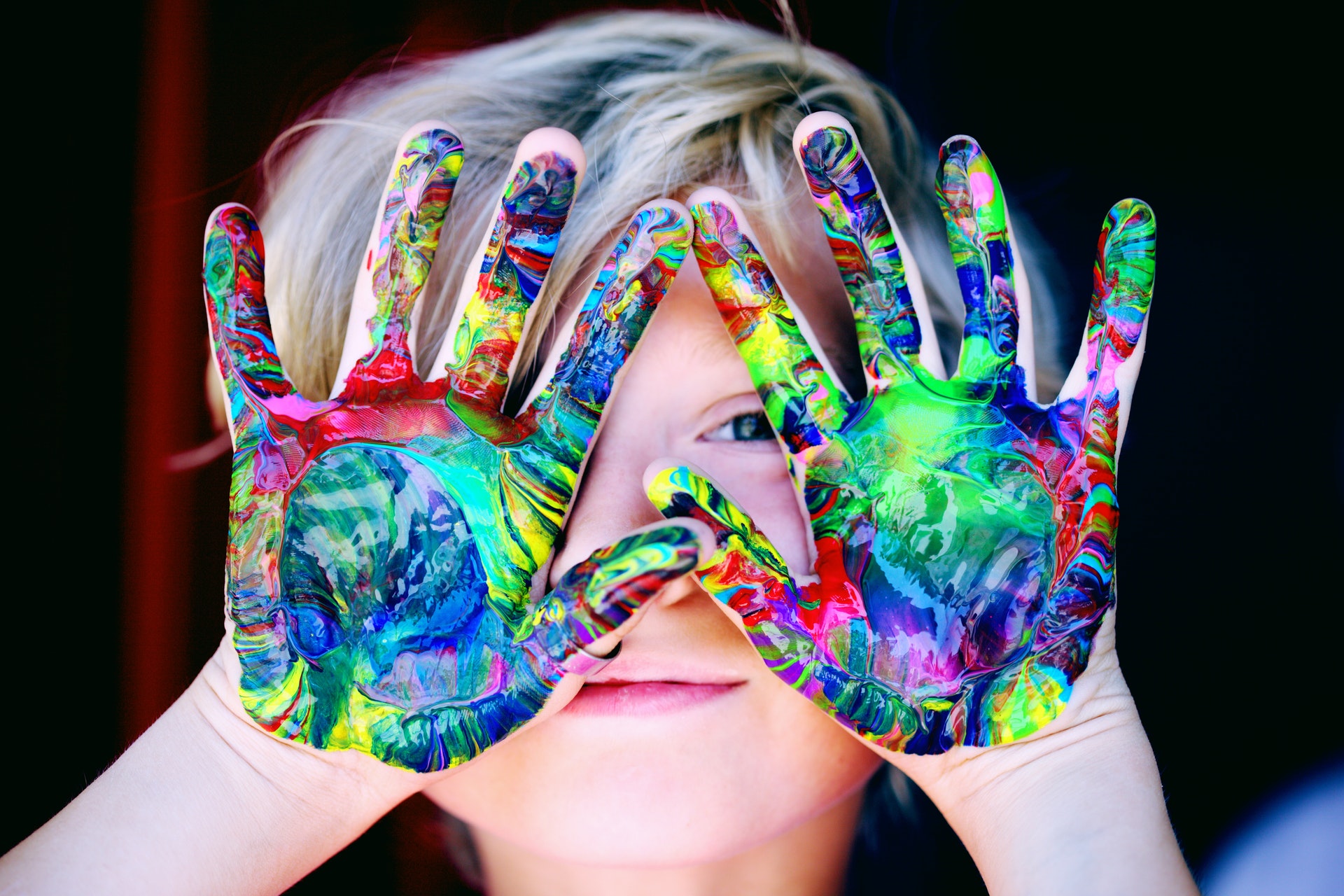 A kid with hands dirty with colorful paint after some creative activity